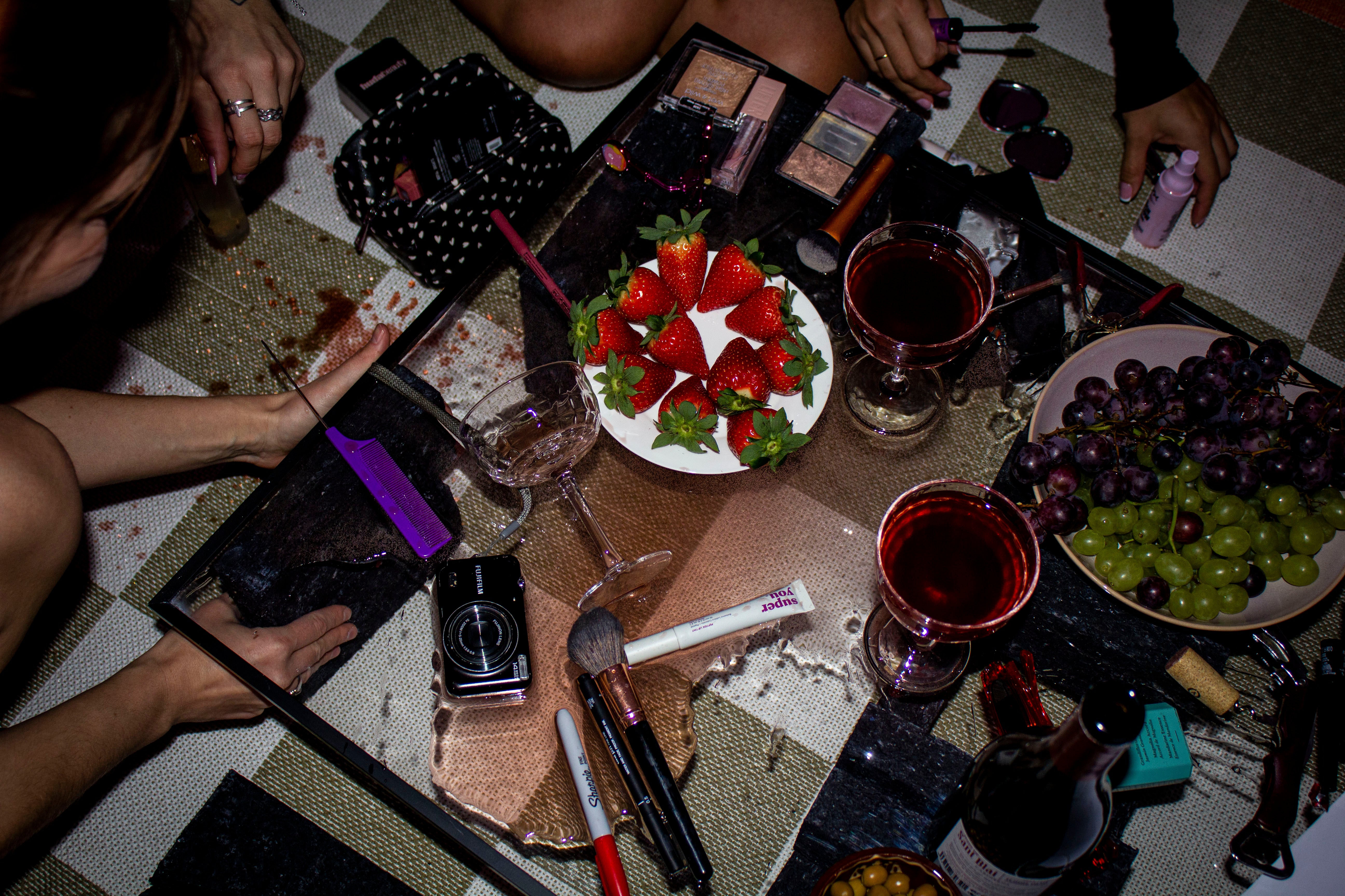 Messy table with wine glasses, lipstick, and snacks – aftermath of girls night out
